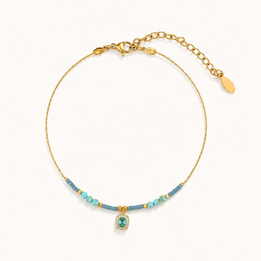 Minimalist blue beaded anklet with K-gold chain and cubic zirconia pendant.