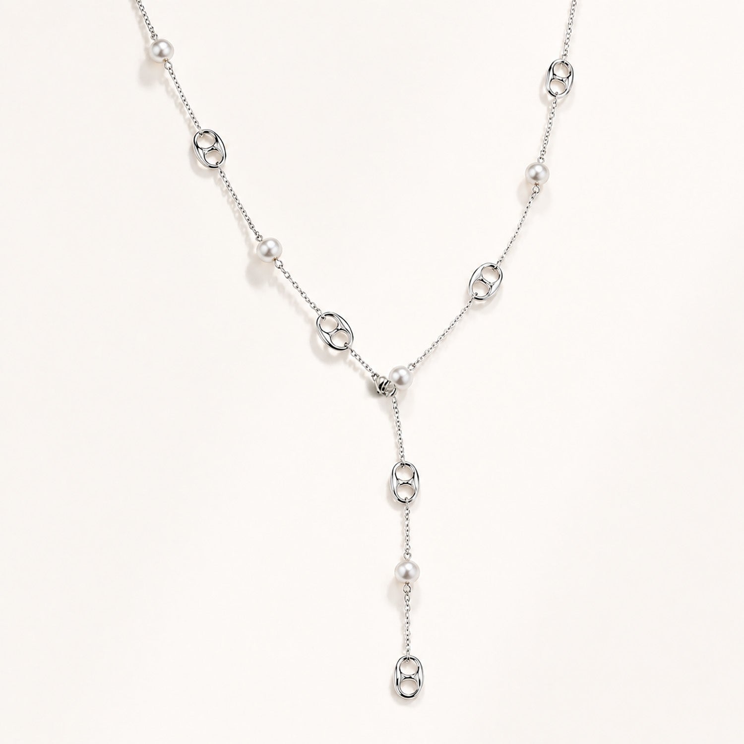 Elegant silver-tone lariat necklace featuring mother-of-pearl and anchor links on a white background.