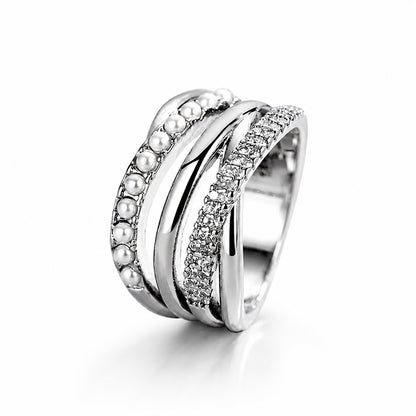 Minimalist studio shot of a complex silver-tone multi-strand ring accented with cubic zirconia and crystal pearls on a clean white background.