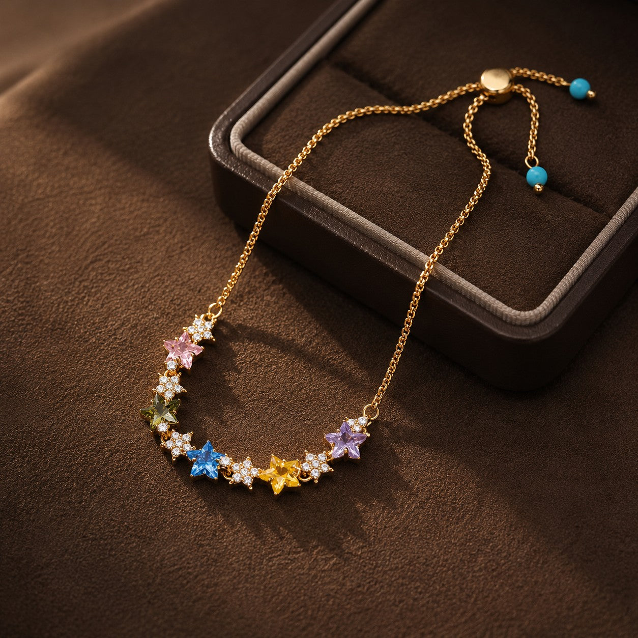 Close-up of multicolor star cubic zirconia gold drawstring slider bracelet displayed on brown velvet jewelry box