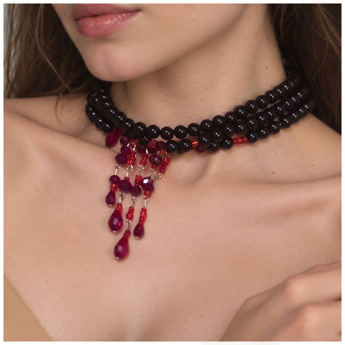 Close-up of model wearing jet black pearl choker necklace with red crystal blood drips for vampire style