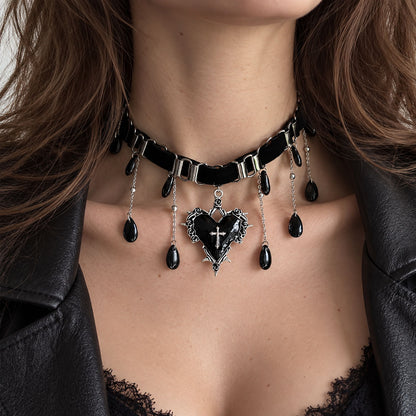 Model wearing gothic black cross heart dangle earrings with silver bow detail