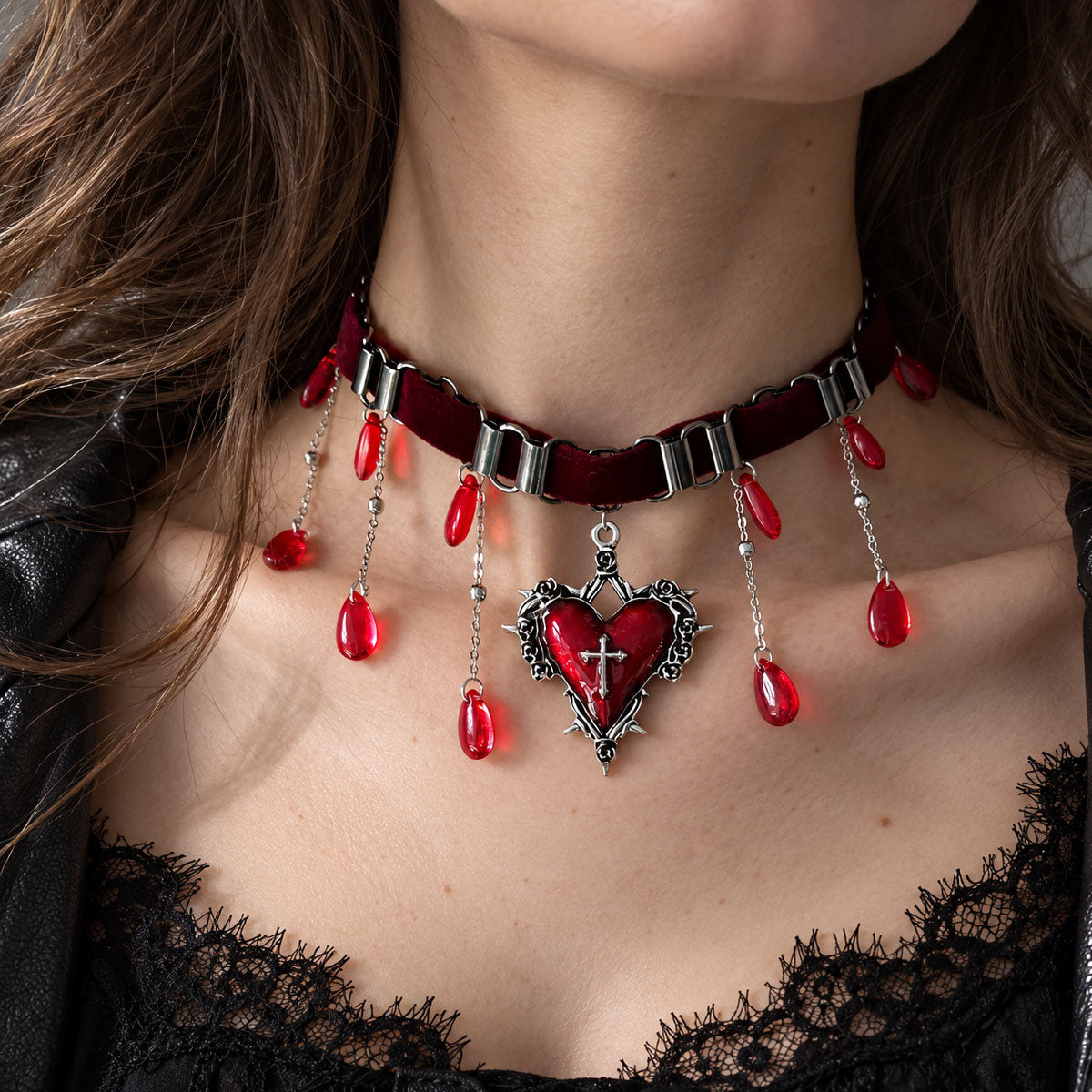 Model wearing gothic red cross heart dangle earrings with silver bow detail