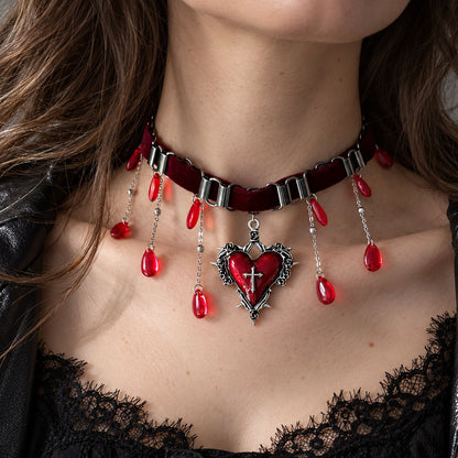 Model wearing gothic red cross heart dangle earrings with silver bow detail