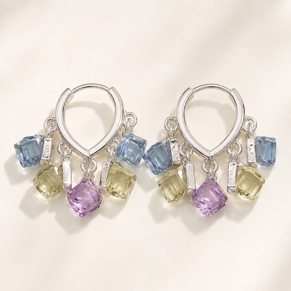 Pair of silver finished huggie hoop earrings featuring dangling pastel blue, yellow, and purple sugar cube crystals