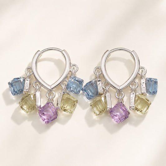 Pair of silver finished huggie hoop earrings featuring dangling pastel blue, yellow, and purple sugar cube crystals