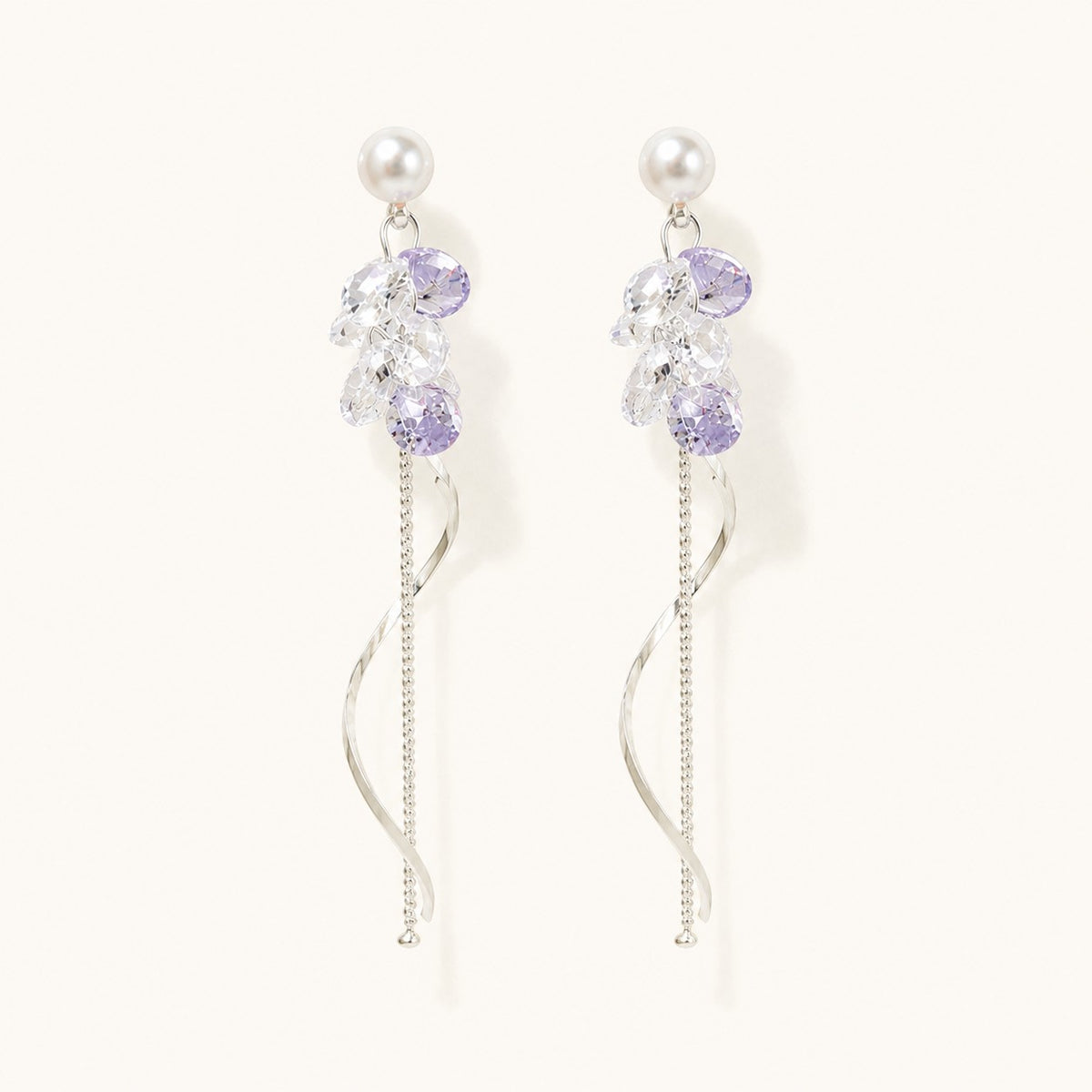 Pair of silver long drop earrings with pearl studs, lavender crystal cluster, and spiral wave tassel on white background