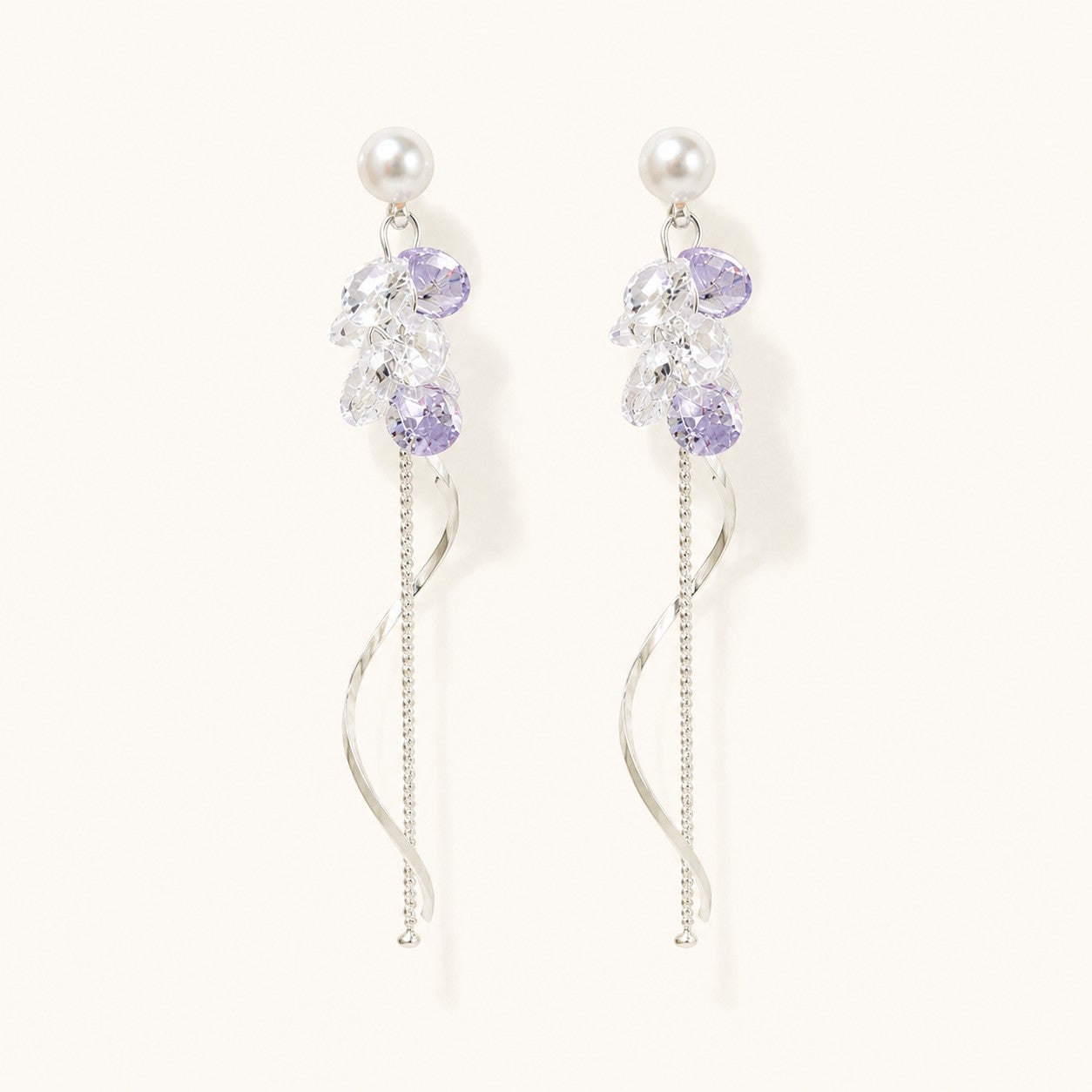 Pair of silver long drop earrings with pearl studs, lavender crystal cluster, and spiral wave tassel on white background