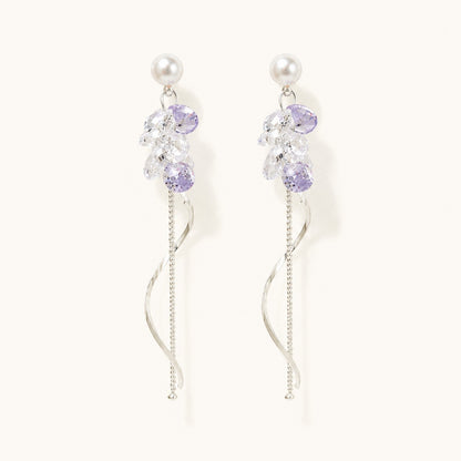 Pair of silver long drop earrings with pearl studs, lavender crystal cluster, and spiral wave tassel on white background