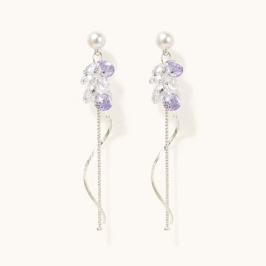 Pair of silver long drop earrings with pearl studs, lavender crystal cluster, and spiral wave tassel on white background