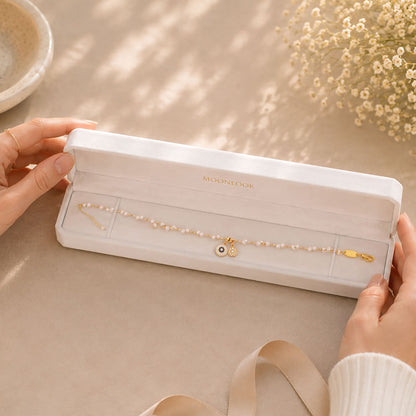 Hands opening a premium white Moonlook jewelry box containing a gold-tone pearl necklace.