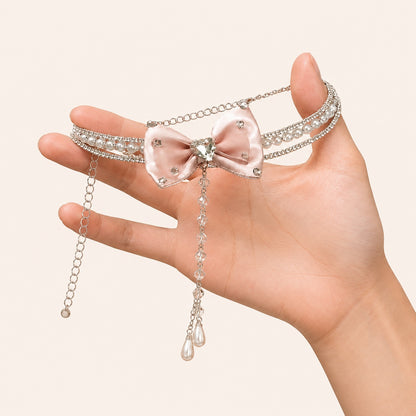 Hand holding pink satin bow pearl choker necklace with rhinestone strands and dangling teardrops