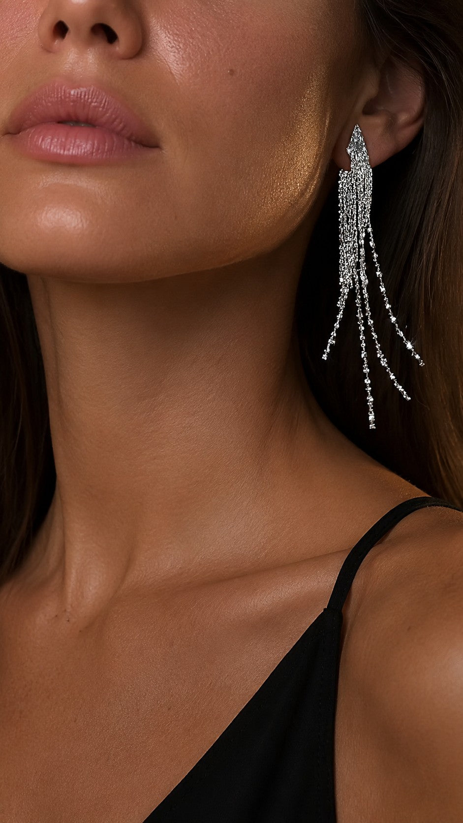 Model wearing long silver crystal waterfall tassel earrings paired with a black silk strap dress.