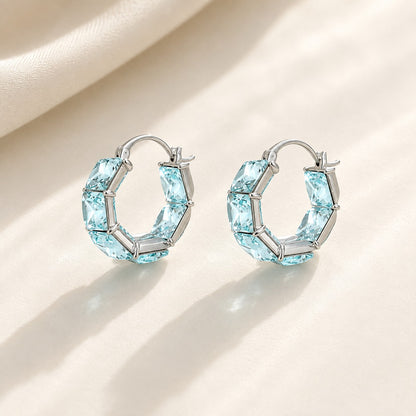 Pair of 2cm platinum-plated ocean ice blue square-cut CZ crystal hoop earrings on cream background