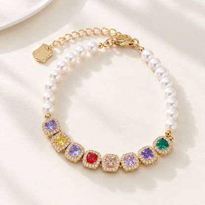 Flatlay view of gold bracelet with colorful cushion cut CZ gems and white pearls on beige background