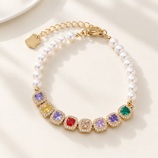 Flatlay view of gold bracelet with colorful cushion cut CZ gems and white pearls on beige background