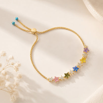 18K gold plated rainbow star cubic zirconia adjustable bolo slider bracelet with turquoise accent beads on beige surface