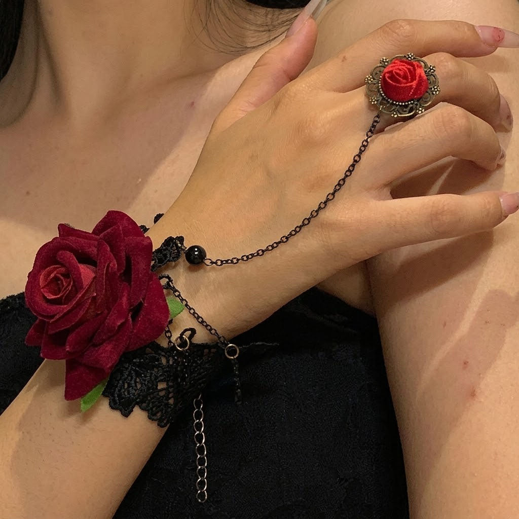 Close-up view of gothic black lace hand harness bracelet with red rose ring on model's hand