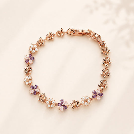 Flatlay view of a rose gold wisteria flower bracelet with lavender CZ crystals and pearls