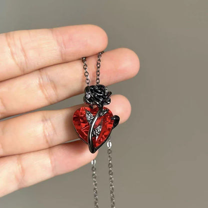 Hand holding the vintage black rose and red crystal heart pendant showcasing product scale and details