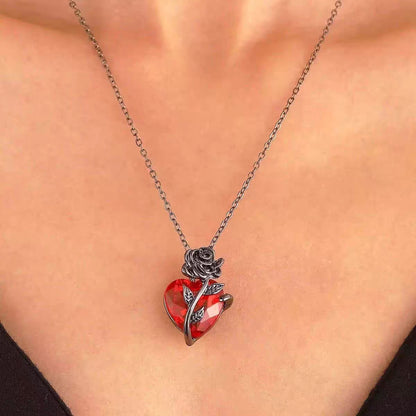 Close-up of model wearing black metal rose red crystal heart necklace on collarbone