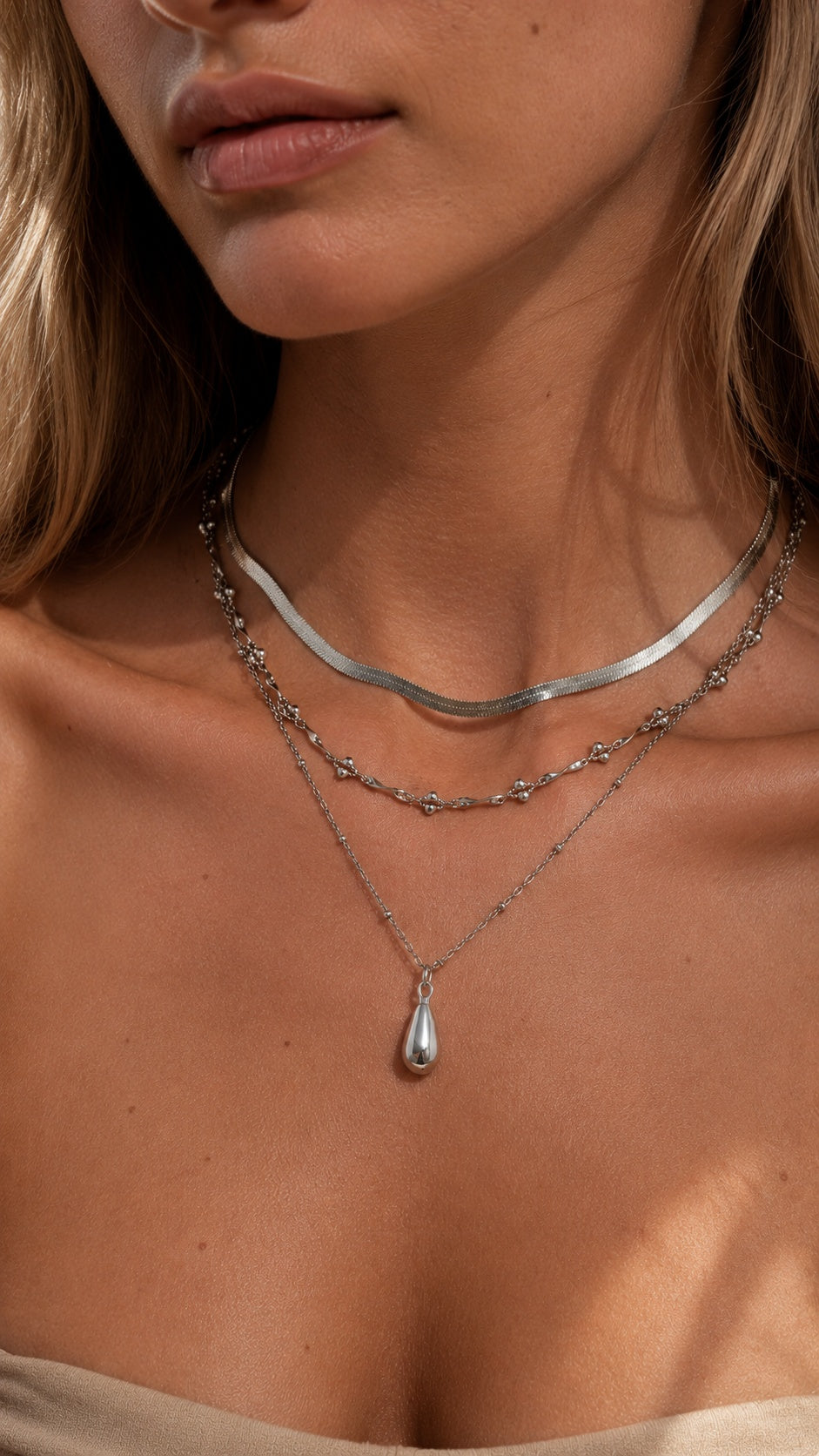 Model wearing 3 piece silver layered teardrop pendant necklace stack with snake chain