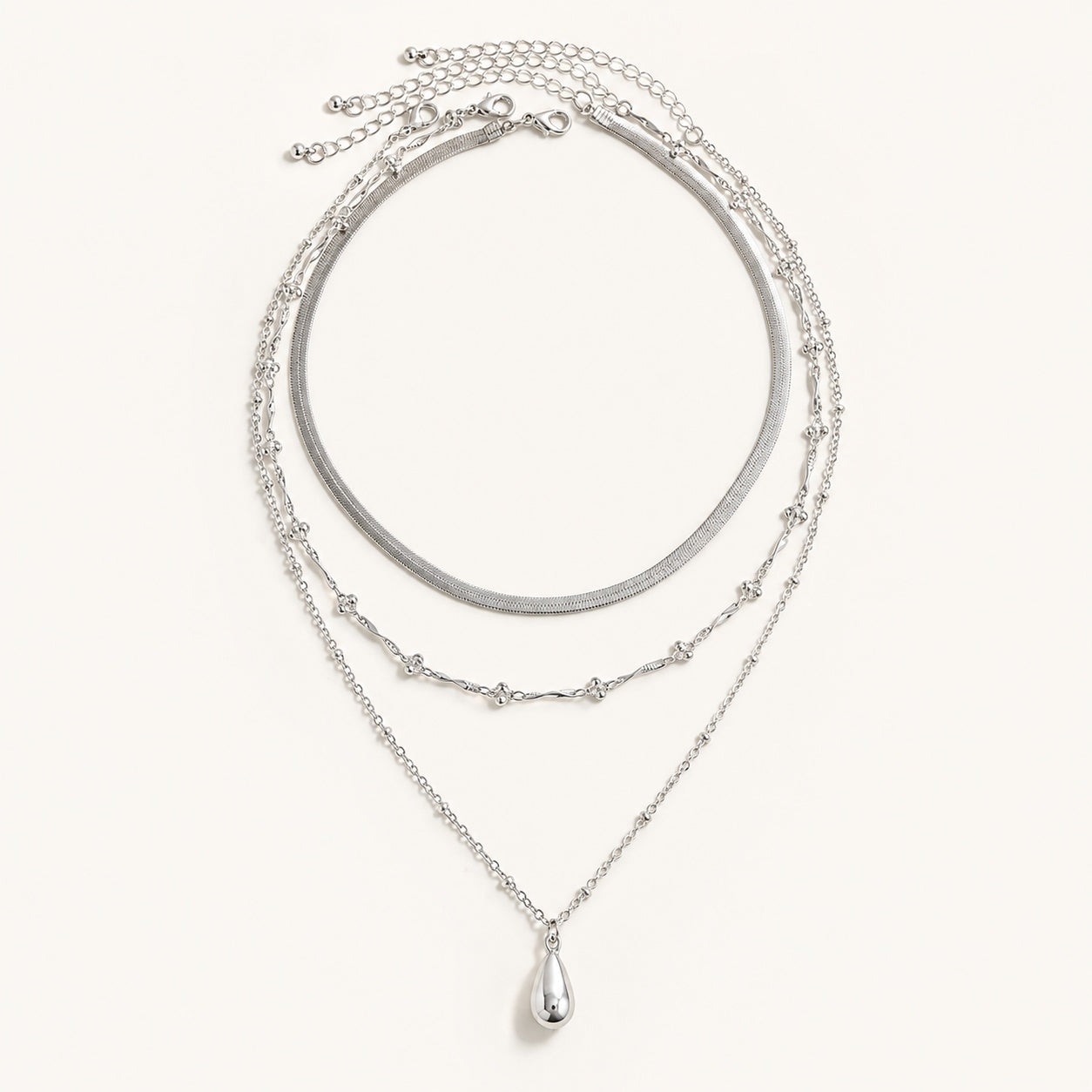 Silver 3 piece layered necklace set featuring snake chain and teardrop pendant on white background