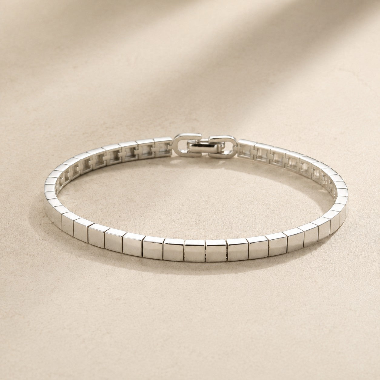 High-shine silver mirror ice cube block link bracelet with fold-over clasp on beige silk