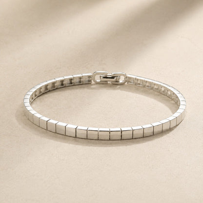 High-shine silver mirror ice cube block link bracelet with fold-over clasp on beige silk