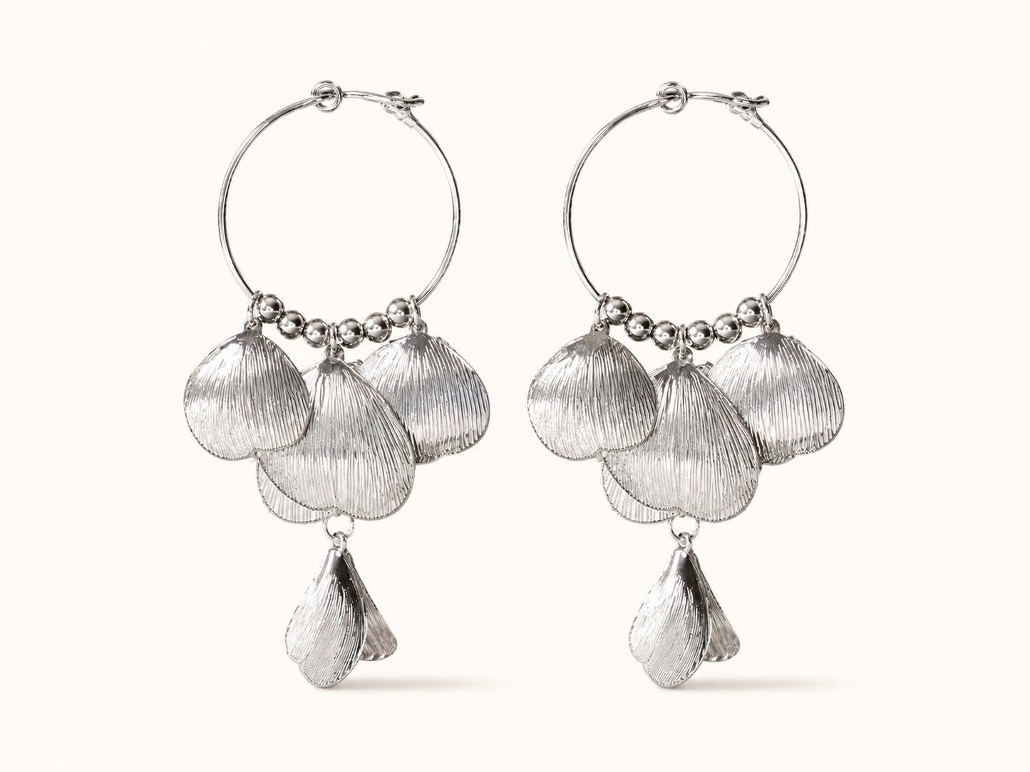 Pair of silver-plated hoop earrings featuring cascading textured leaf and shell petals on a plain background.