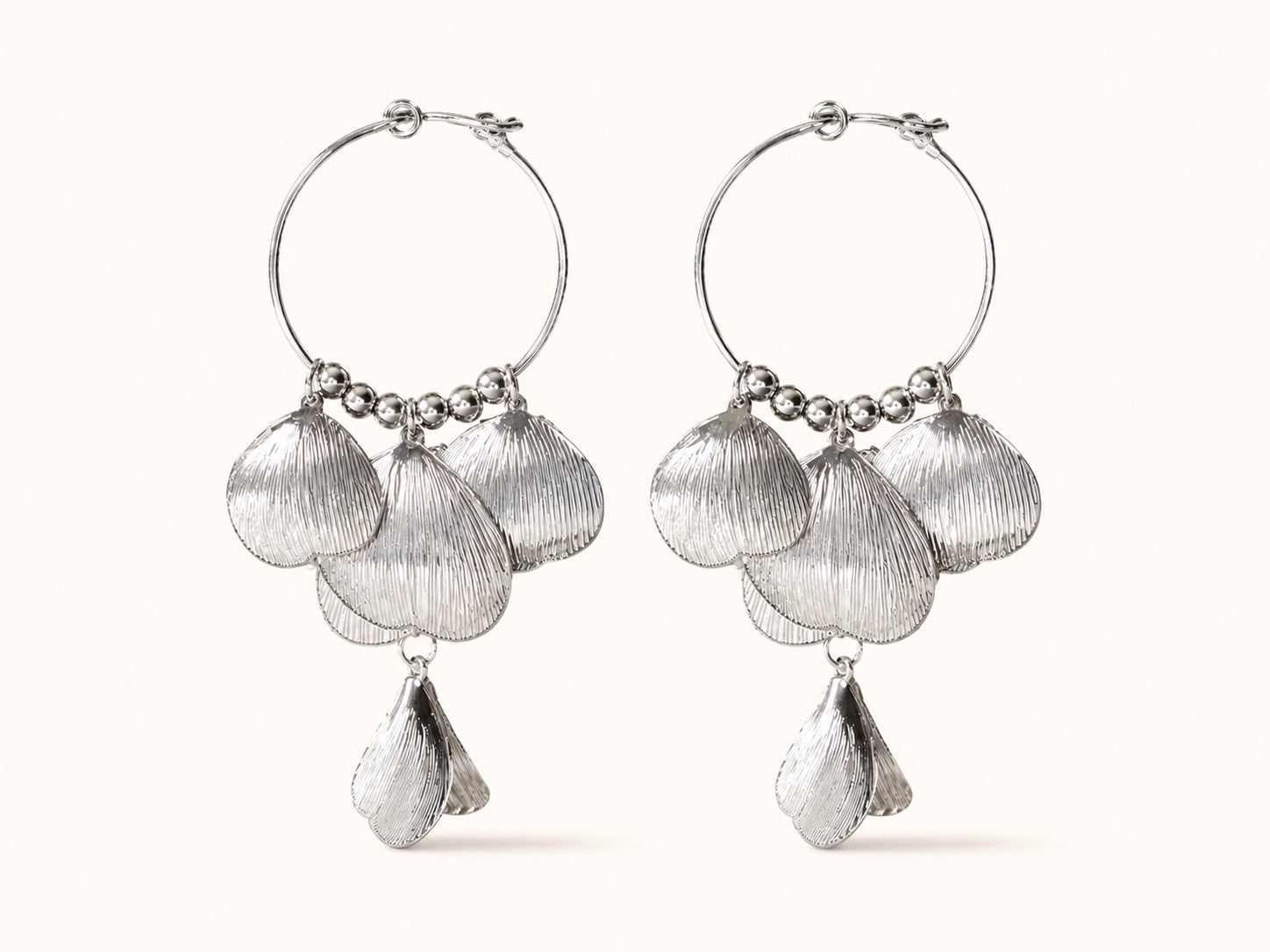 Pair of silver-plated hoop earrings featuring cascading textured leaf and shell petals on a plain background.