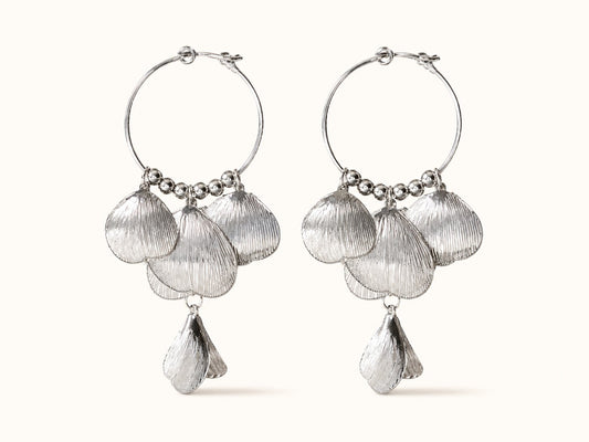 Pair of silver-plated hoop earrings featuring cascading textured leaf and shell petals on a plain background.