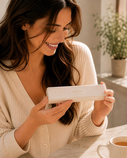 Smiling woman looking at a beautiful pearl lariat necklace inside a white Moonlook gift box.