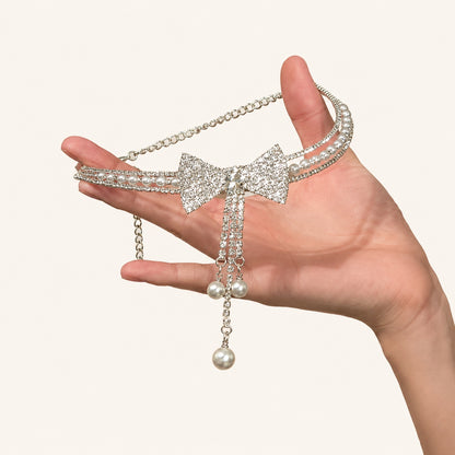 Handheld shot of rhinestone bow pearl choker necklace with crystal tassels on neutral background