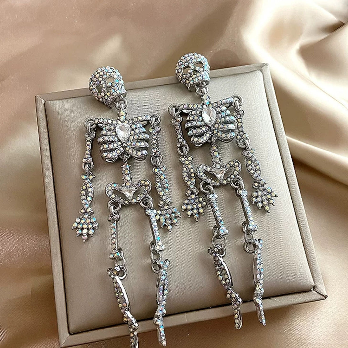 Flat lay view of sparkling full rhinestone skeleton dangle earrings on beige gift box