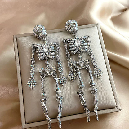 Flat lay view of sparkling full rhinestone skeleton dangle earrings on beige gift box