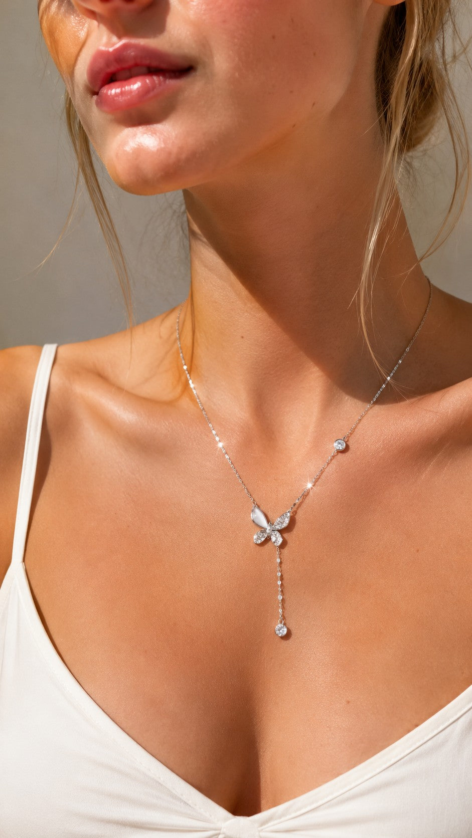 Model gracefully touching her collarbone highlighting the delicate silver butterfly drop pendant and sparkling CZ accents.