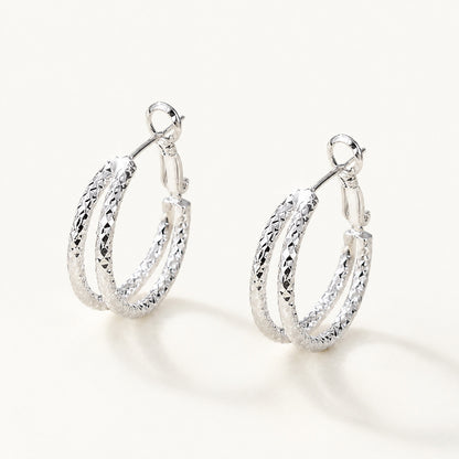 Minimalist textured double hoop earrings in a sleek white gold-tone on a white background.