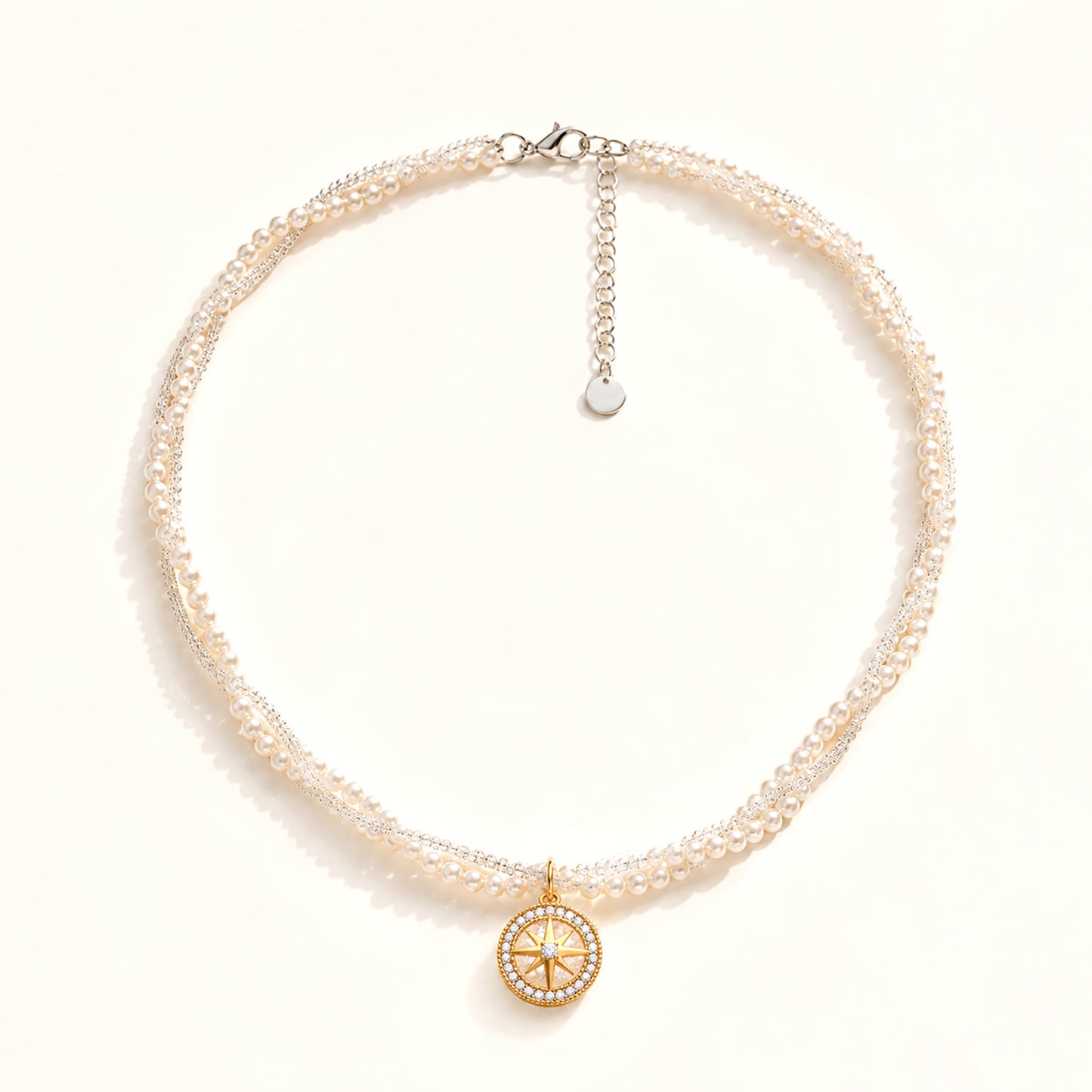 Minimalist flat lay of a double-layer twisted pearl necklace featuring a gold-tone compass and zirconia pendant on a white background.