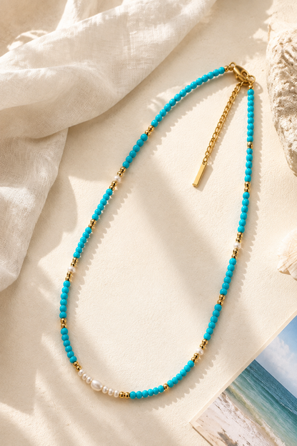 Coastal-inspired beaded necklace strand featuring 3mm turquoise stones and freshwater pearls, resting gracefully on a warm aesthetic stone surface.