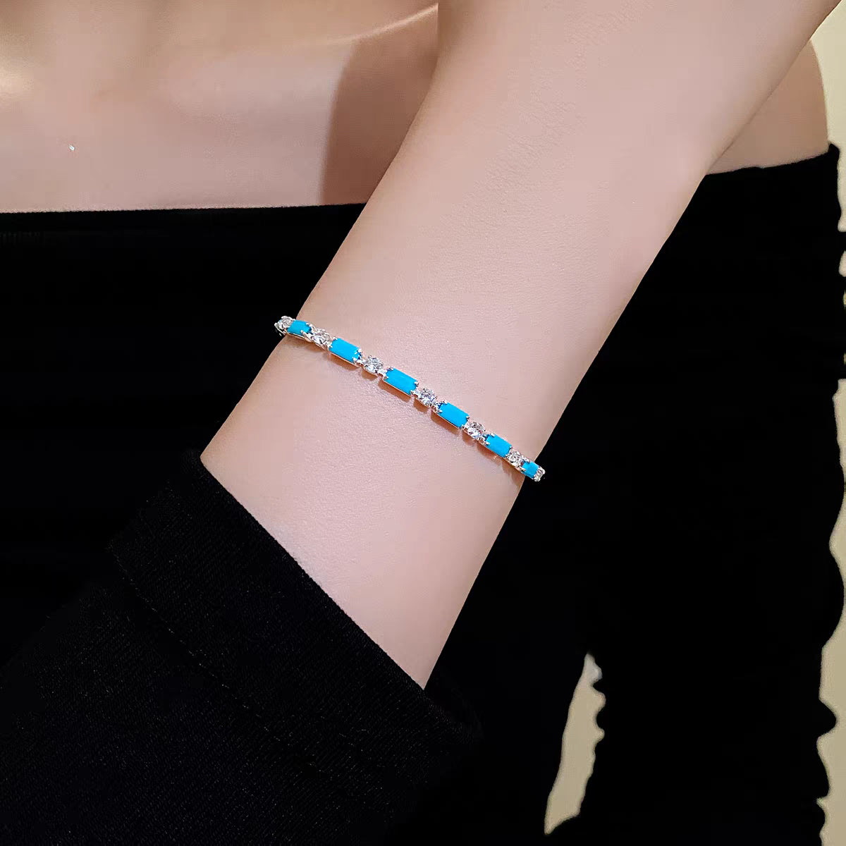 Model wearing bright turquoise blue CZ tennis bracelet styled against black outfit