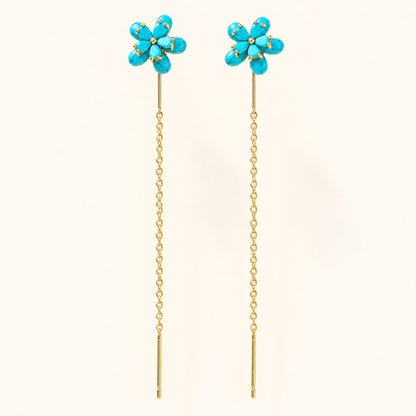 Pair of gold threader drop earrings featuring turquoise blue flower studs on isolated cream background
