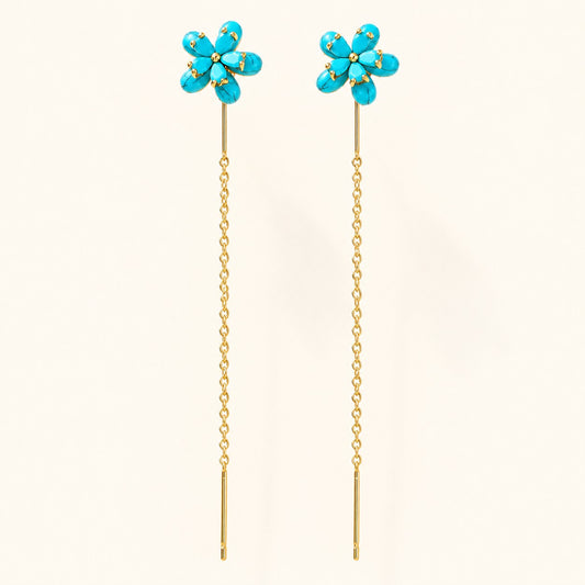 Pair of gold threader drop earrings featuring turquoise blue flower studs on isolated cream background