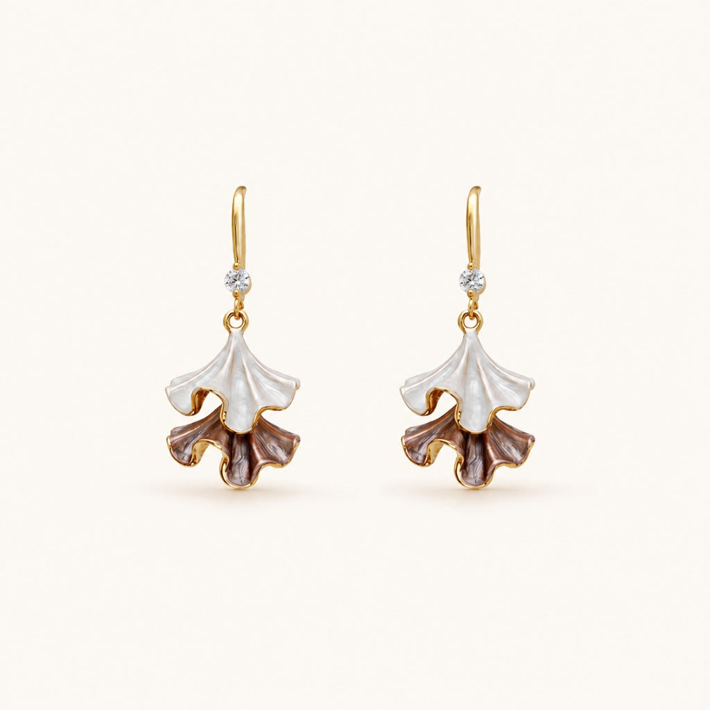 Minimalist flat lay of 18K gold-tone drop earrings featuring two-tiered ruffled petals with a pearlescent white and purple enamel finish on a clean background.