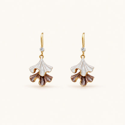 Minimalist flat lay of 18K gold-tone drop earrings featuring two-tiered ruffled petals with a pearlescent white and purple enamel finish on a clean background.