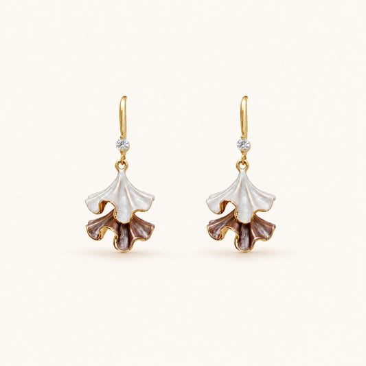 Minimalist flat lay of 18K gold-tone drop earrings featuring two-tiered ruffled petals with a pearlescent white and purple enamel finish on a clean background.