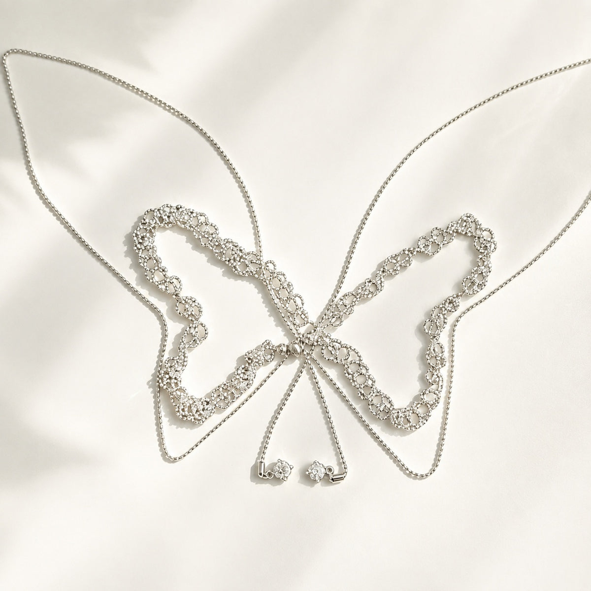 110cm silver lace adjustable slider necklace laid out in a butterfly shape on white silk background
