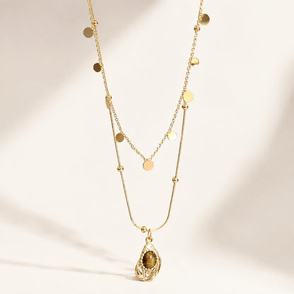 Flatlay view of double layered gold necklace with sequin chain and teardrop resin tiger's eye pendant