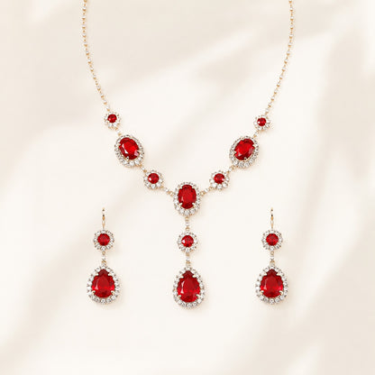 Vintage style simulated ruby teardrop necklace and drop earrings set flat lay on silk