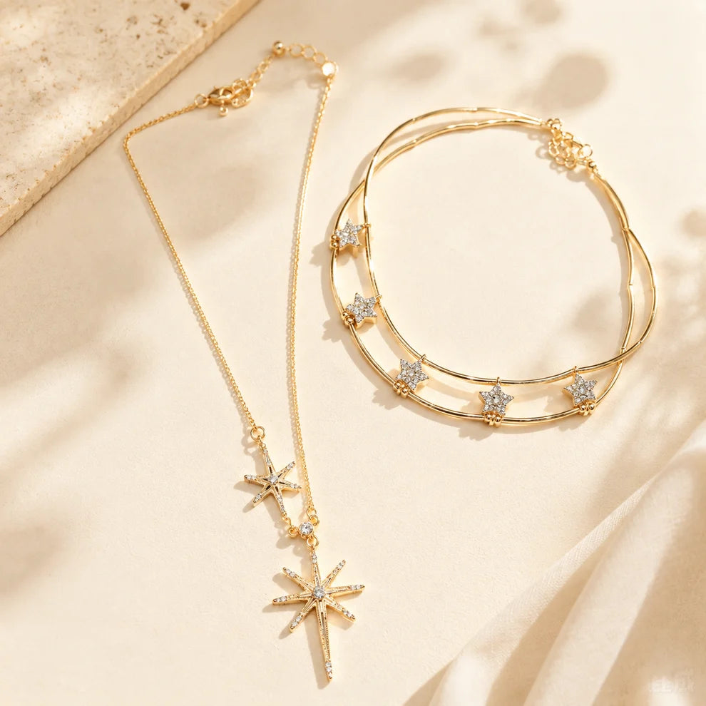 Elegant gold-tone layered necklace with cubic zirconia star and sunburst motifs displayed beautifully on an aesthetic stone and soft silk surface.